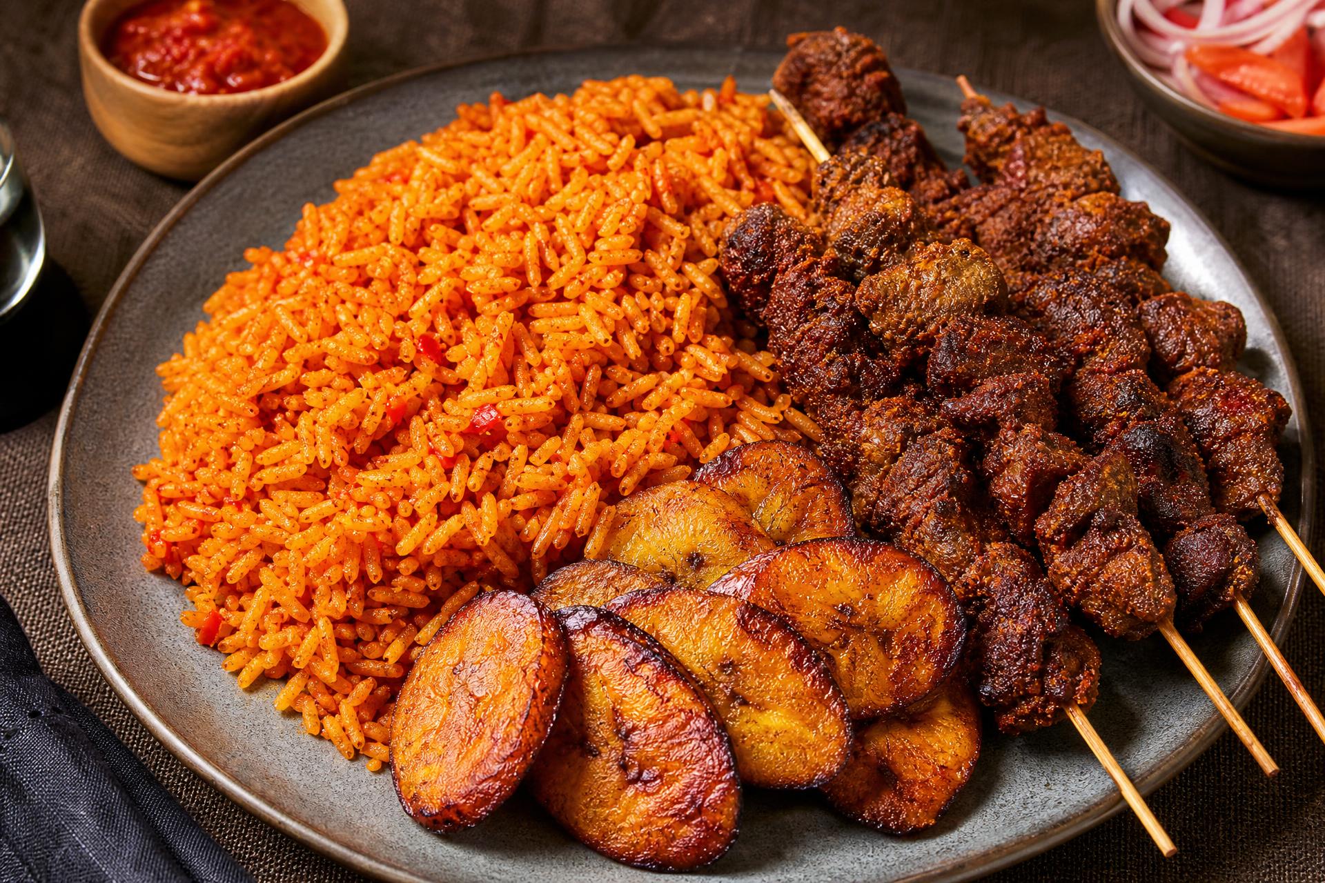 Jollof rice with suya goat meat and fried plantain on a linen tablecloth